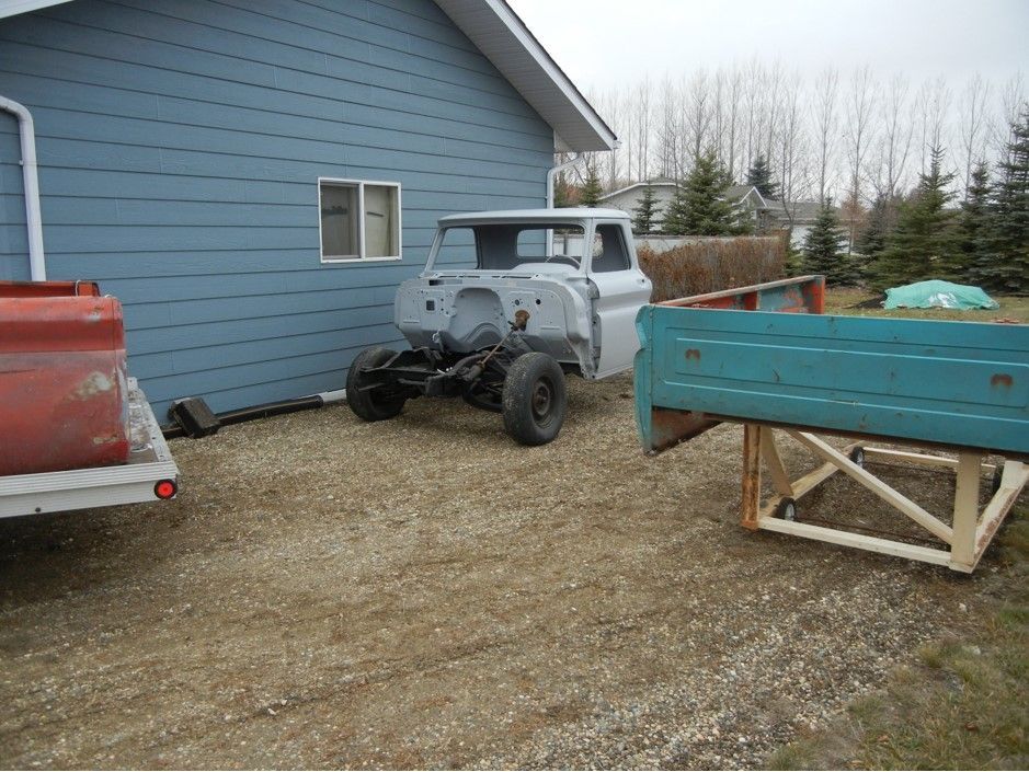 A white truck is parked in front of a blue house