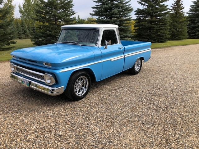A blue and white truck is parked on a gravel road.