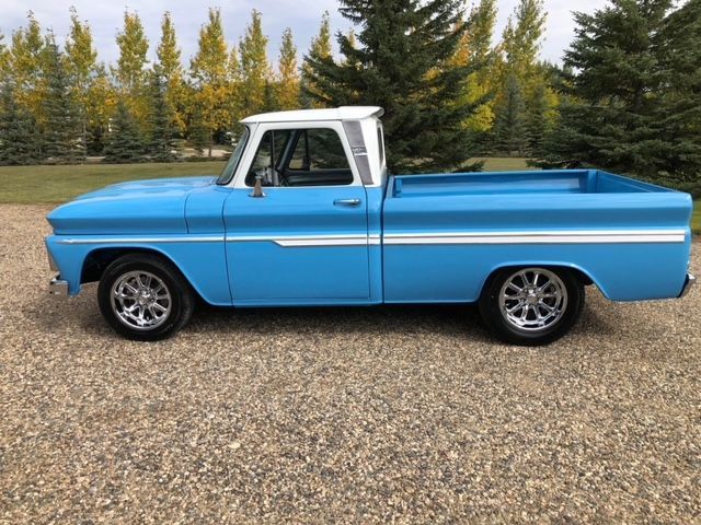 A blue and white truck is parked on a gravel road.