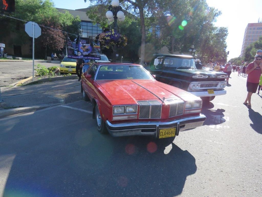 A red car with a texas license plate is parked on the street