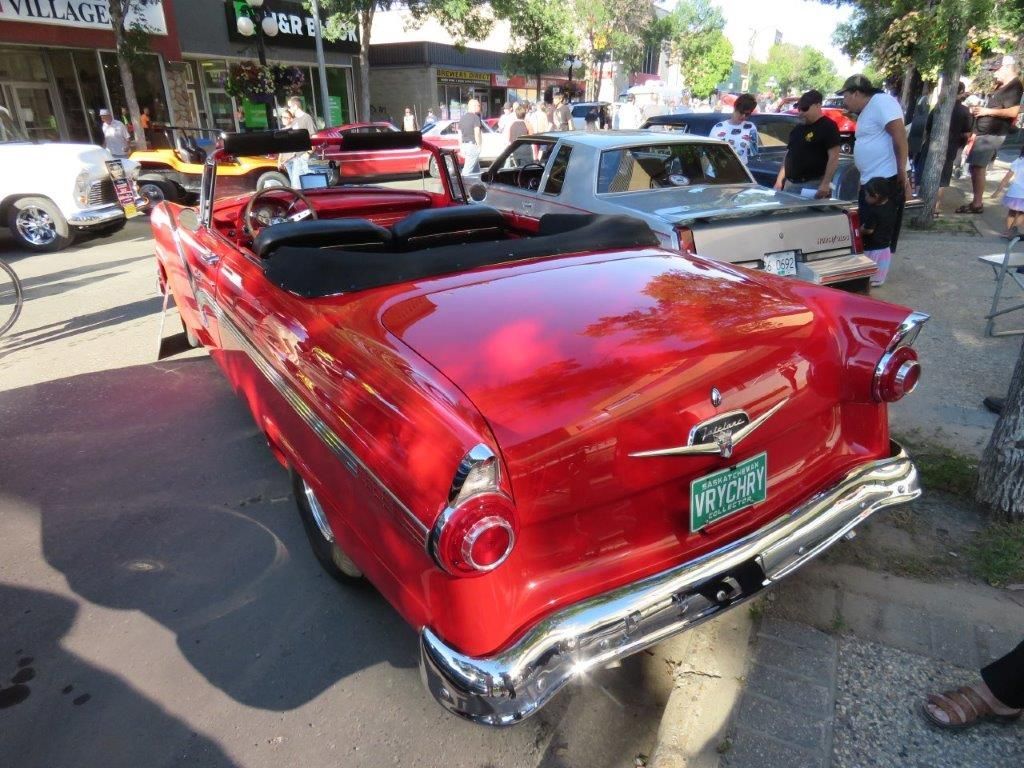 A red convertible car is parked on the side of the road.