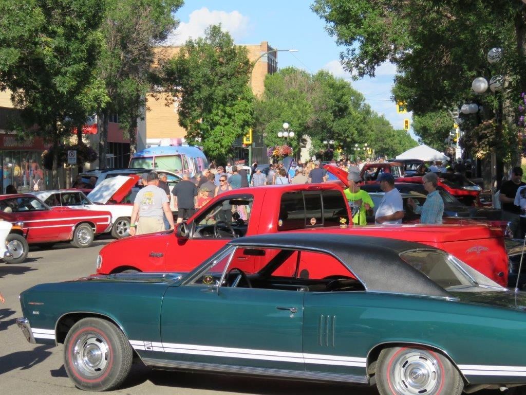 A green car is parked next to a red car at a car show.