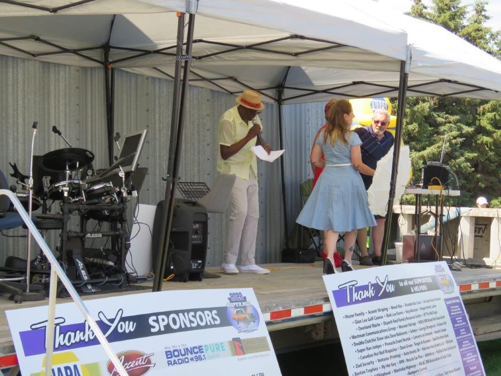 A group of people are standing on a stage under a tent.