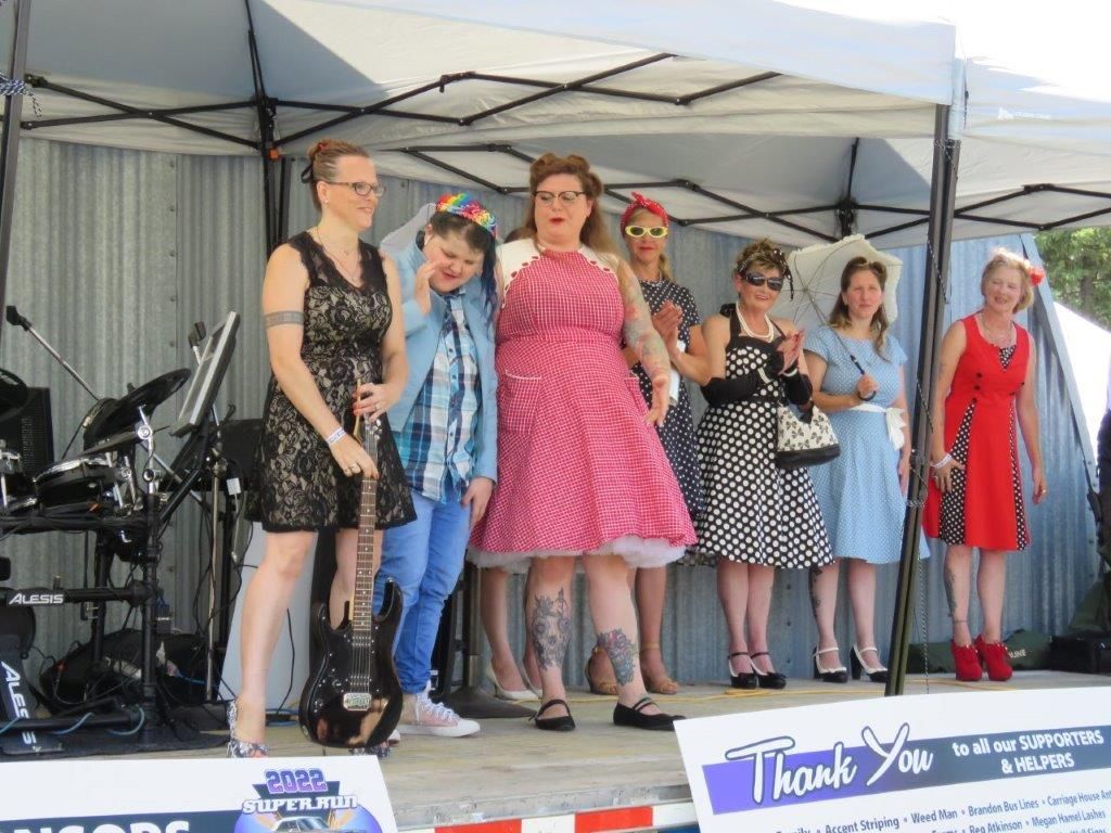 A group of women are standing on a stage in front of a thank you sign.