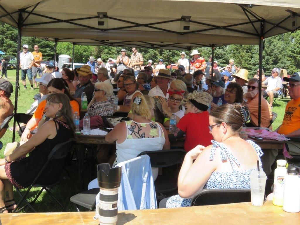 A large group of people are sitting at tables under a tent.