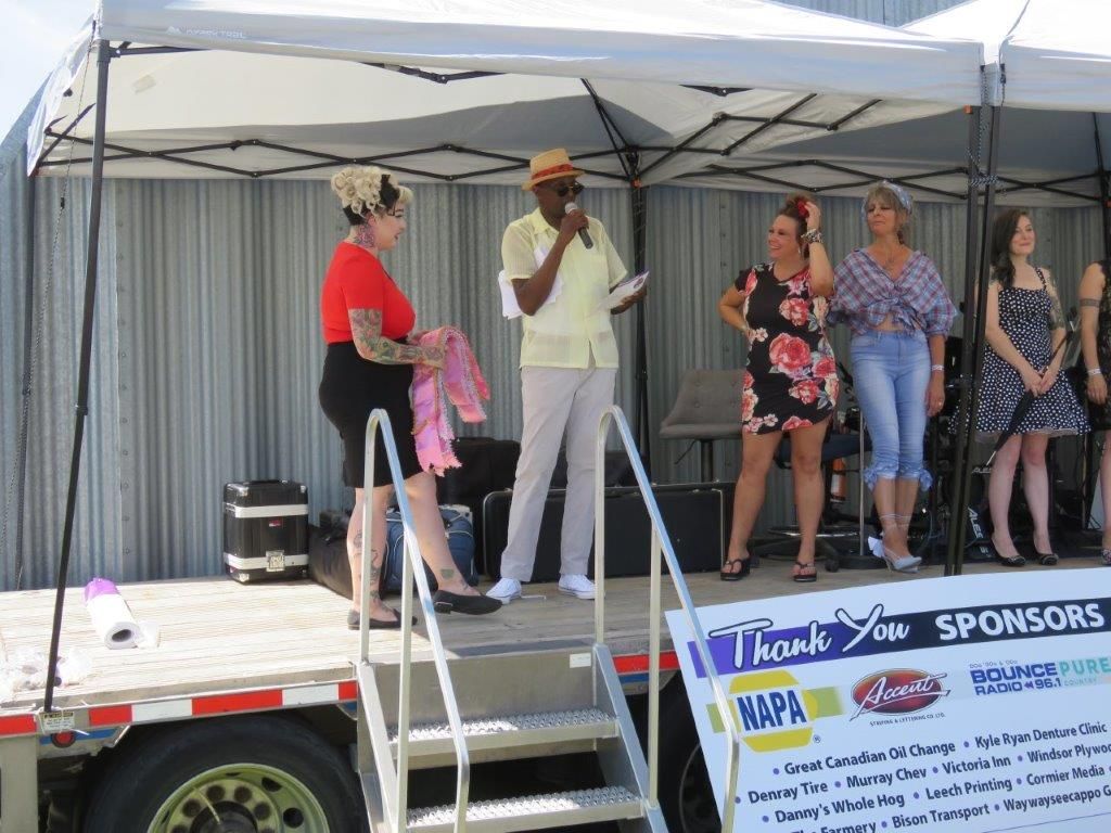A man is standing on a stage giving a speech to a group of women.