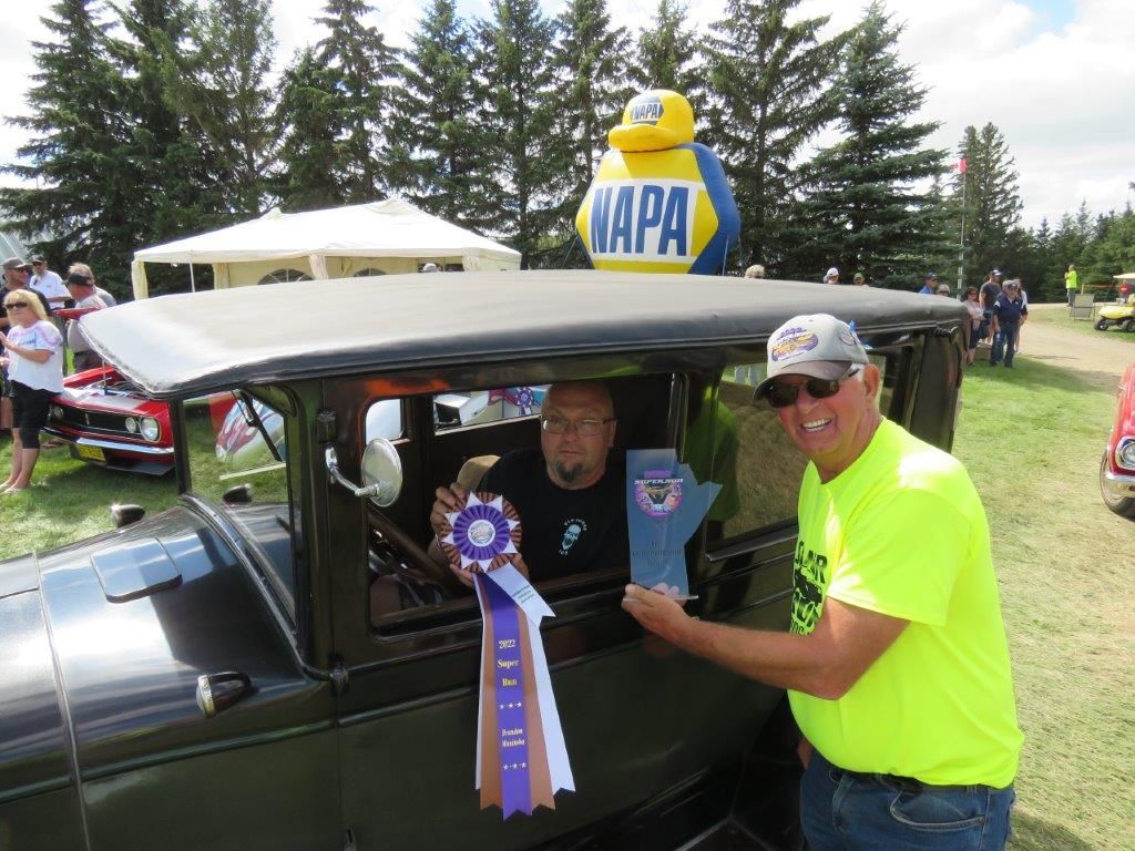 A man is giving a trophy to another man in a car.