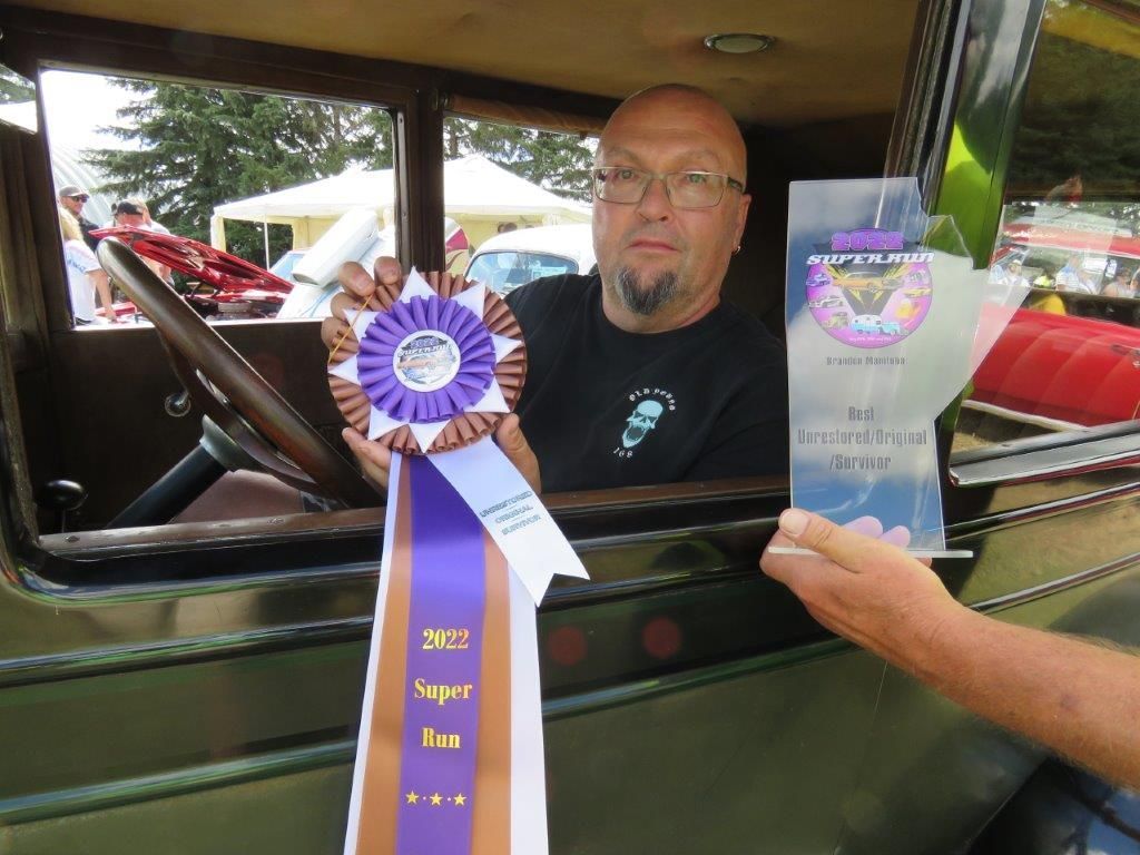 A man is holding a purple ribbon that says super fan