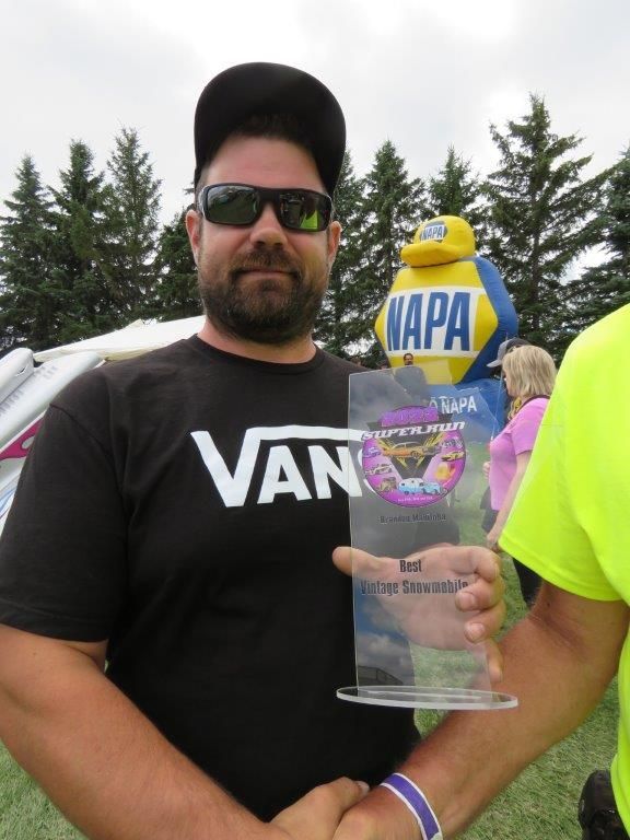 A man wearing a black vans shirt is holding a trophy