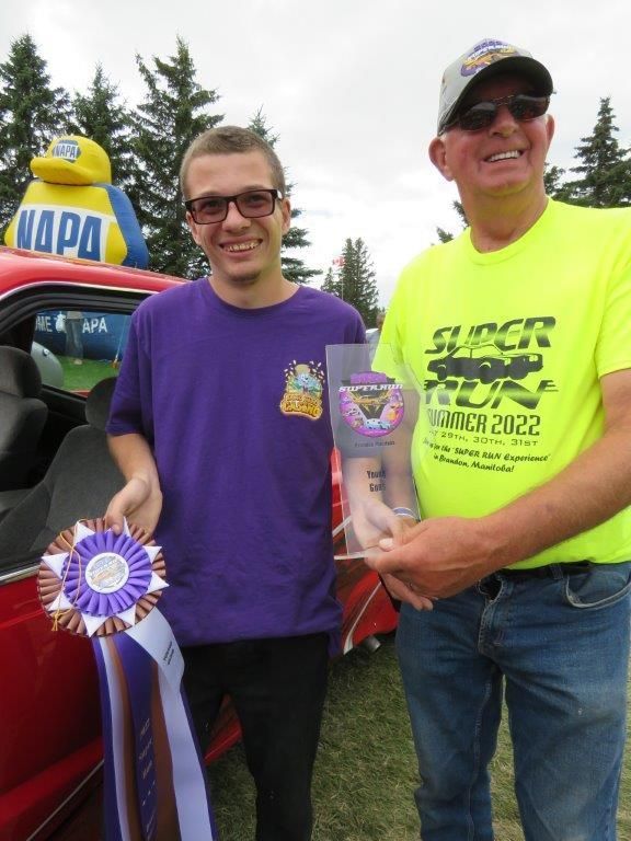 A man wearing a napa shirt stands next to another man
