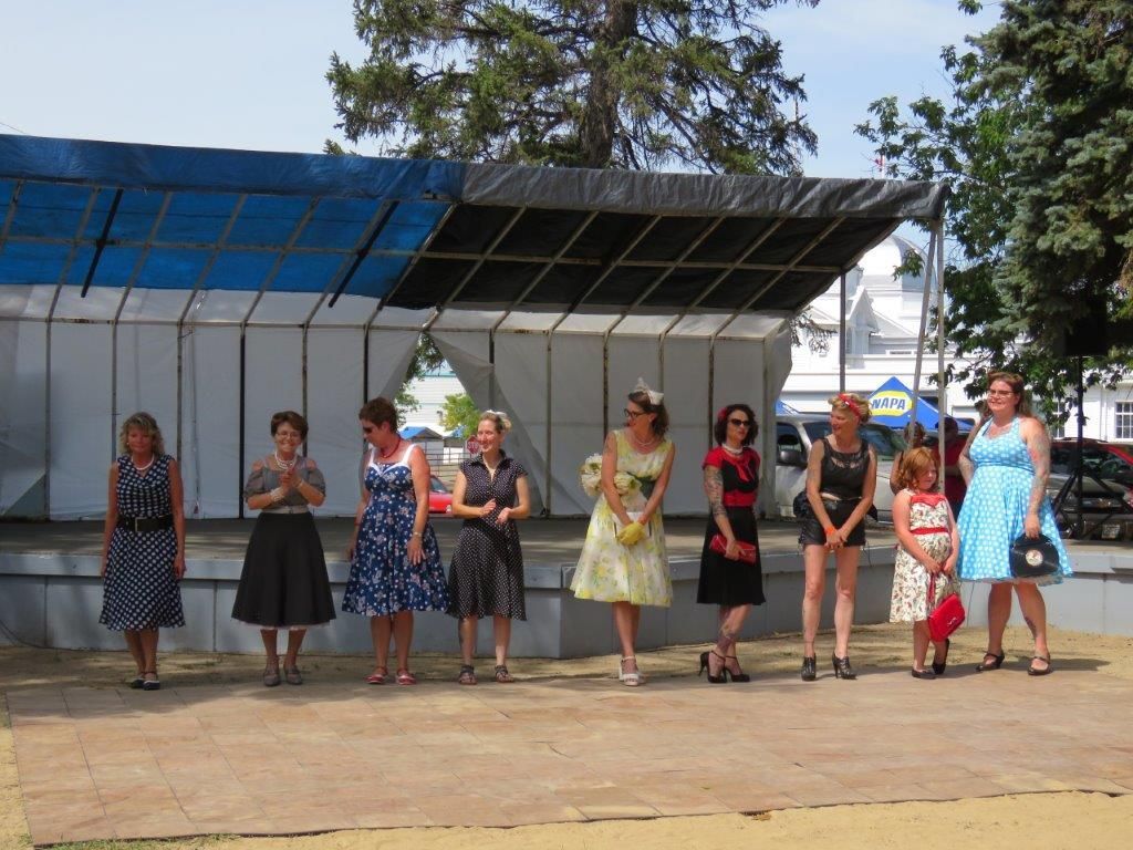 A group of women in dresses are standing in front of a stage.