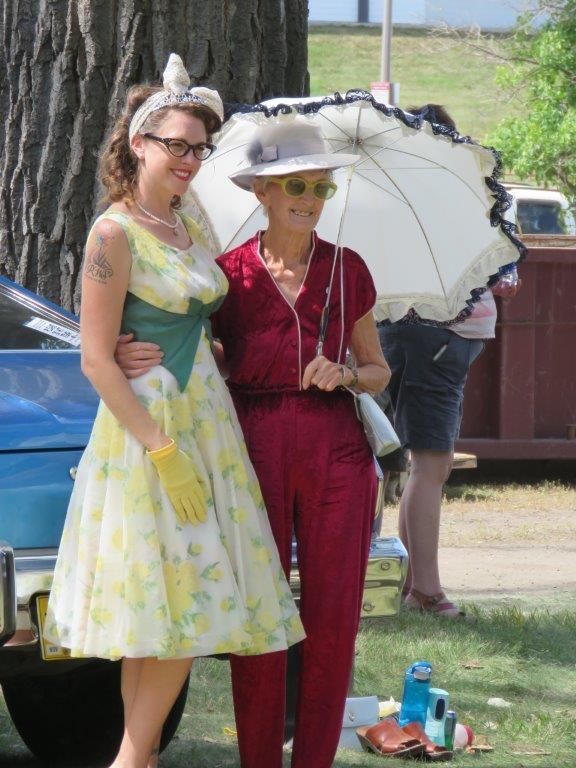 Two women standing next to each other holding an umbrella