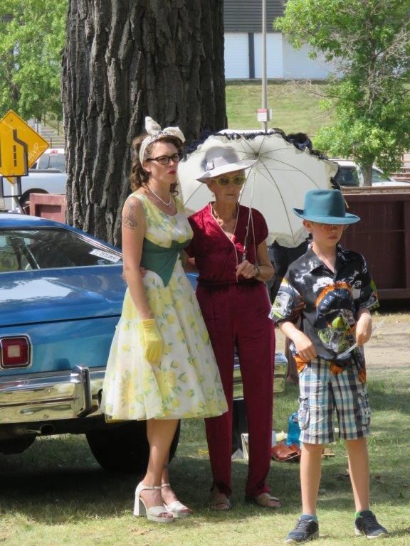 A group of people standing in front of a blue car