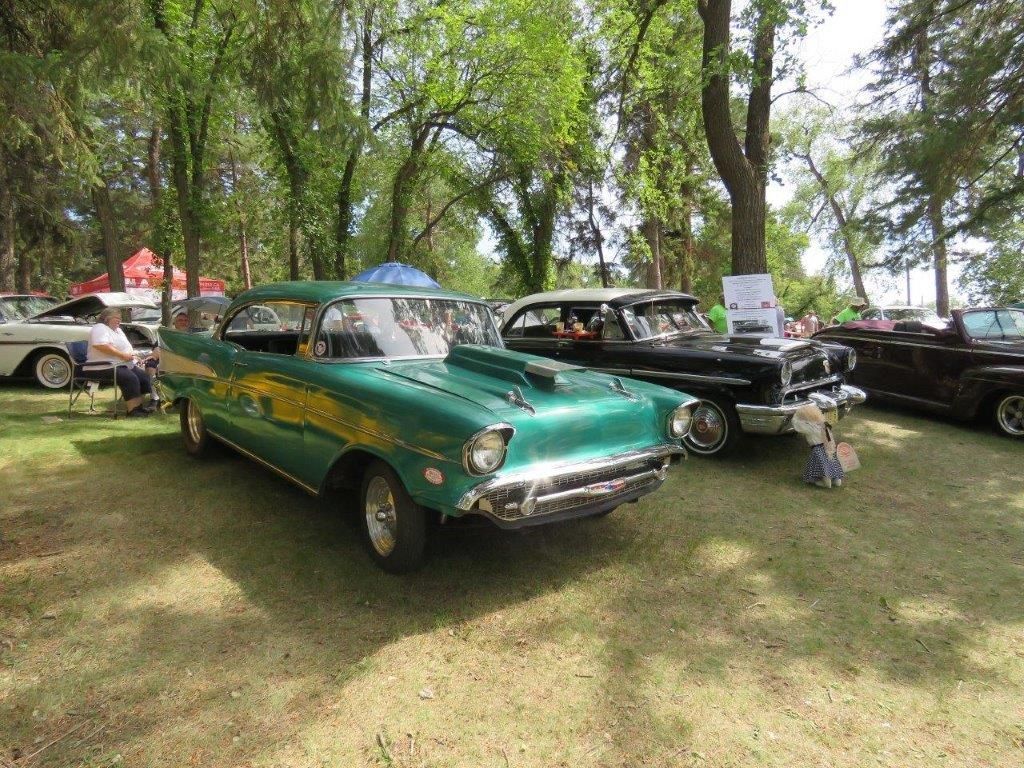 A green car is parked next to a black car at a car show.