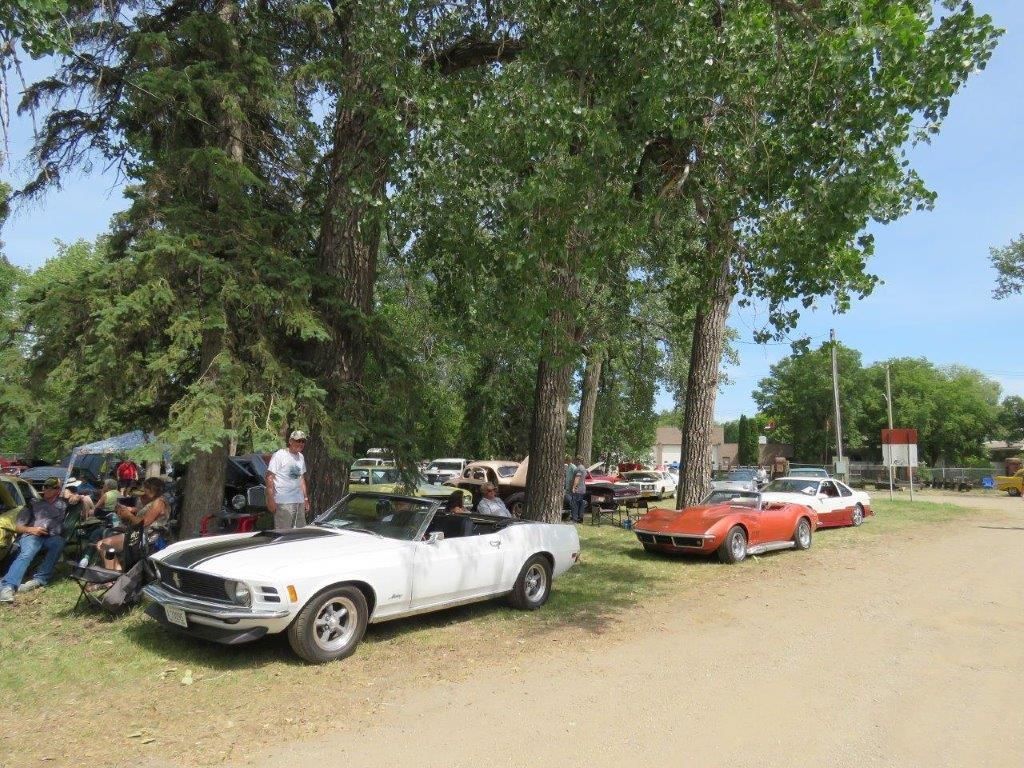 A white car is parked next to a red car in a parking lot.