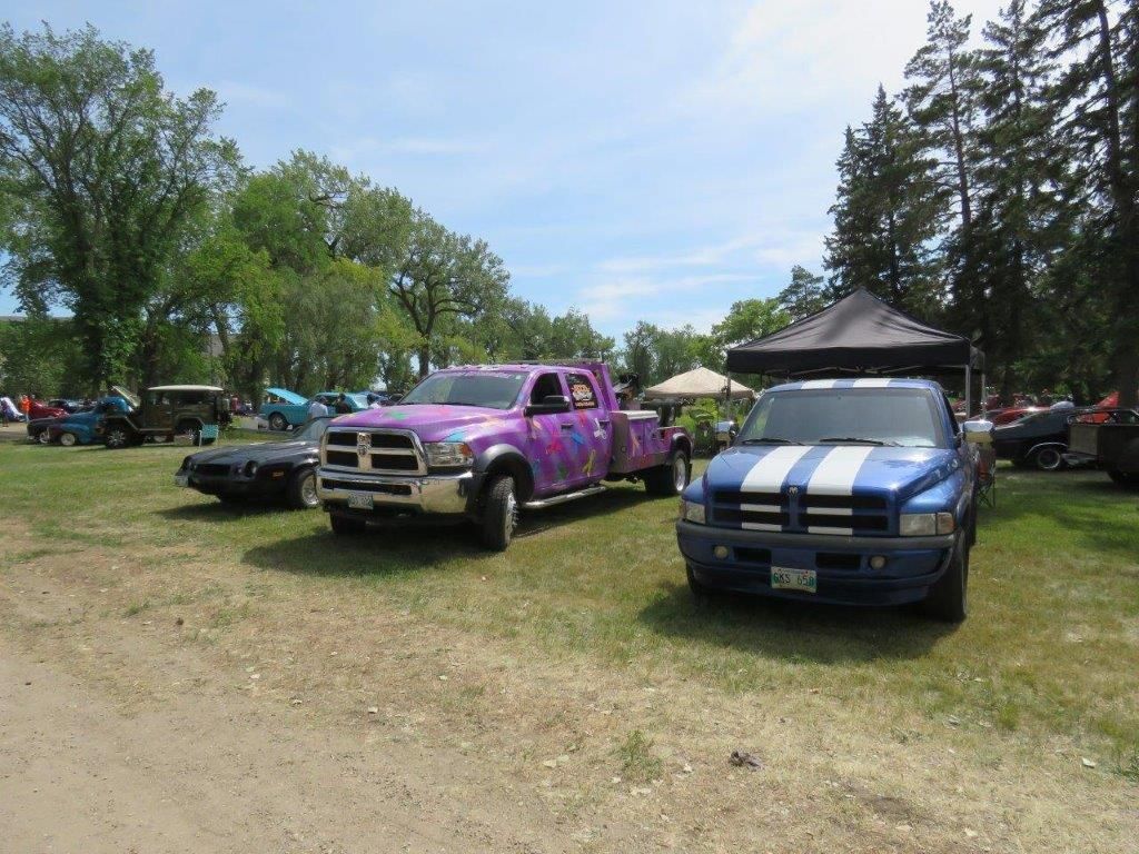 A purple truck is parked next to a blue truck