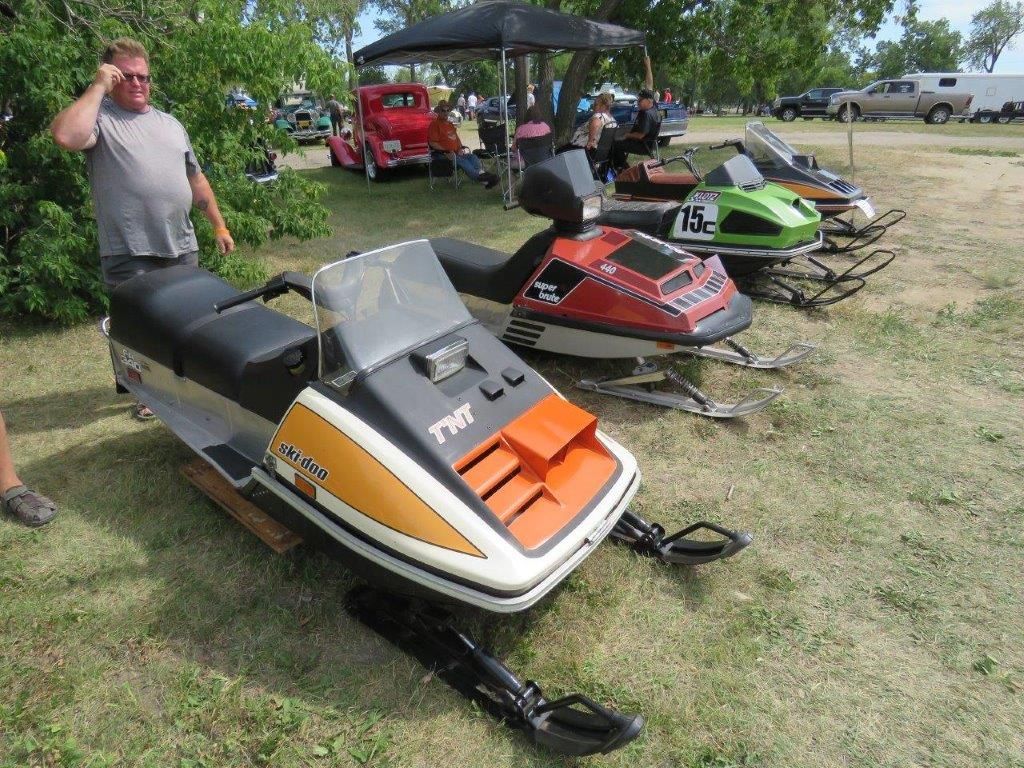 A group of snowmobiles are parked in a grassy field.