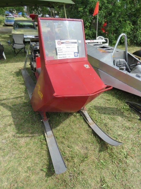 A red snowmobile is parked in a grassy field