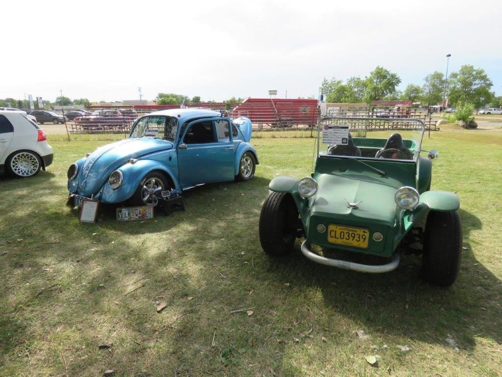 Two cars are parked next to each other in a grassy field.