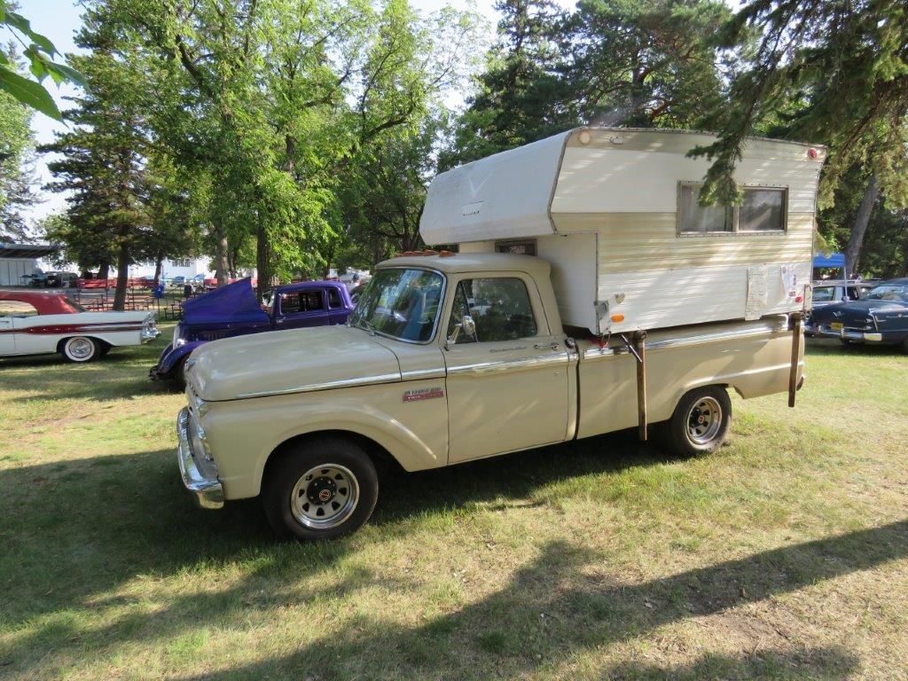 A truck with a camper on top of it is parked in a grassy field.
