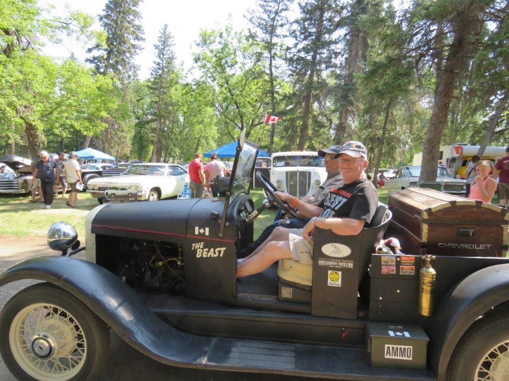 A man is sitting in the driver 's seat of an old car.