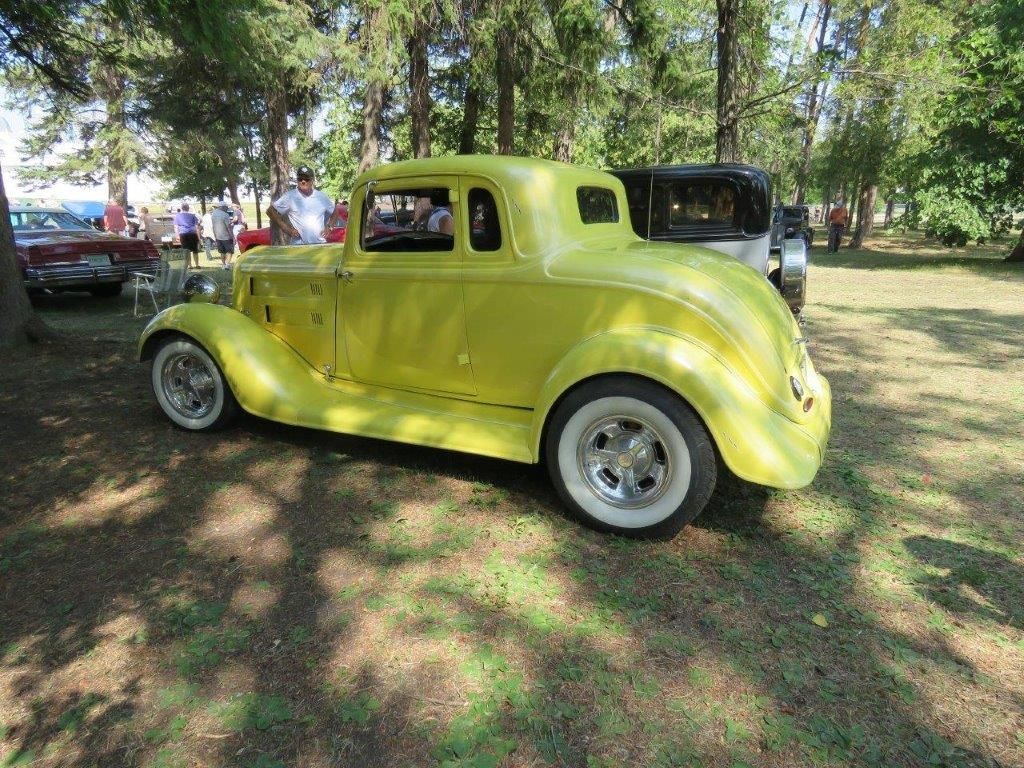 A yellow car is parked in a grassy field.