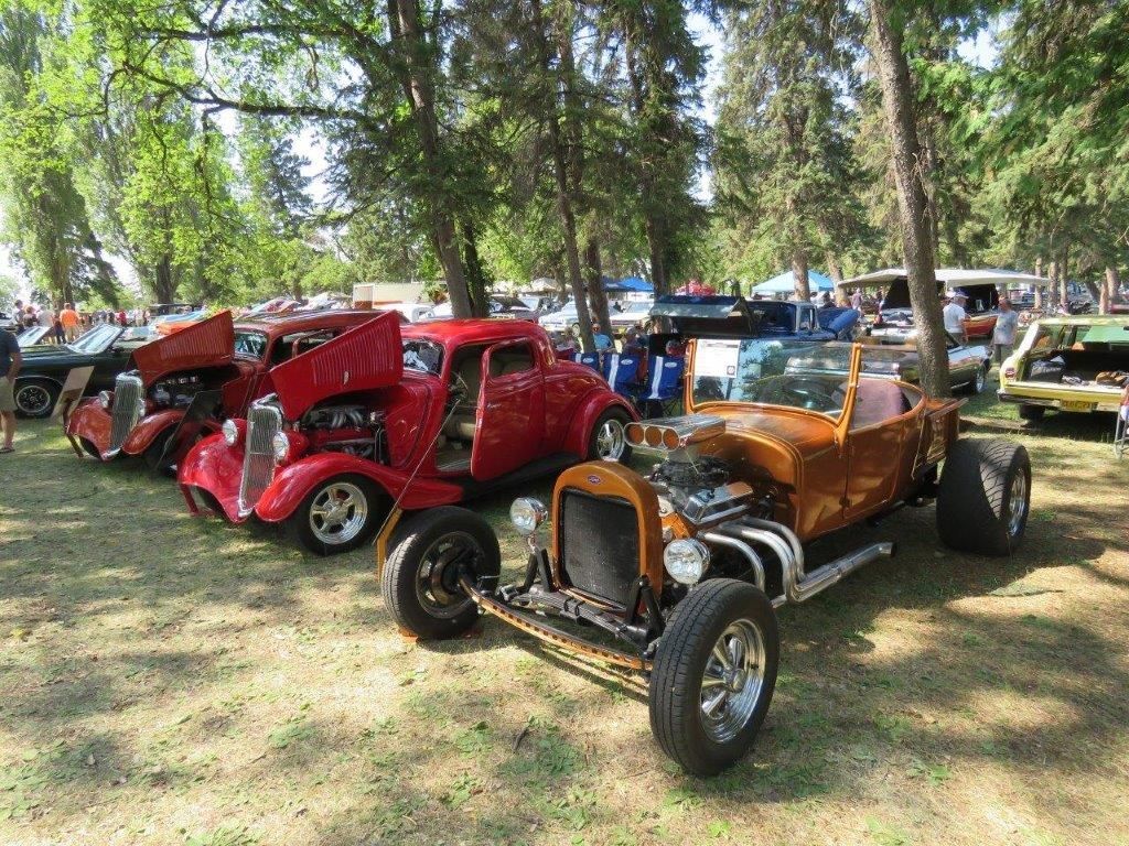 A row of old cars are parked in a grassy field.