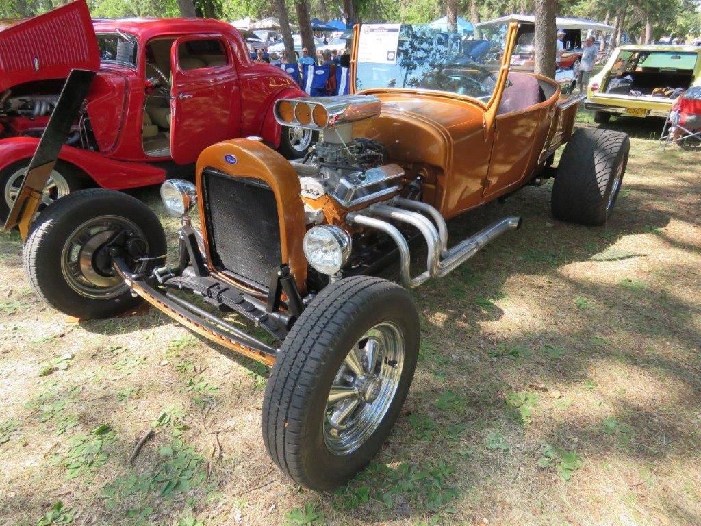 A hot rod is parked next to a red car at a car show.