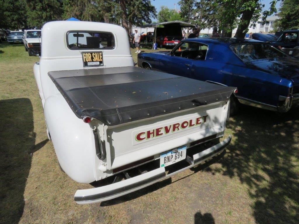 A white chevrolet truck is parked next to a blue car