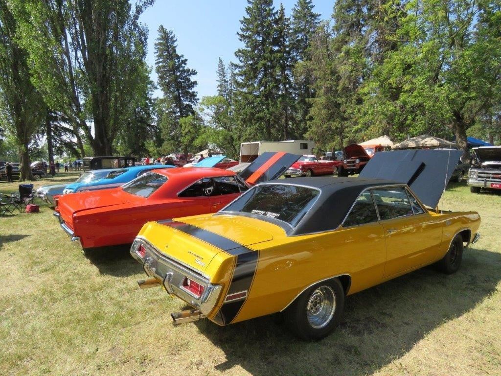 A yellow car is parked next to a red car at a car show