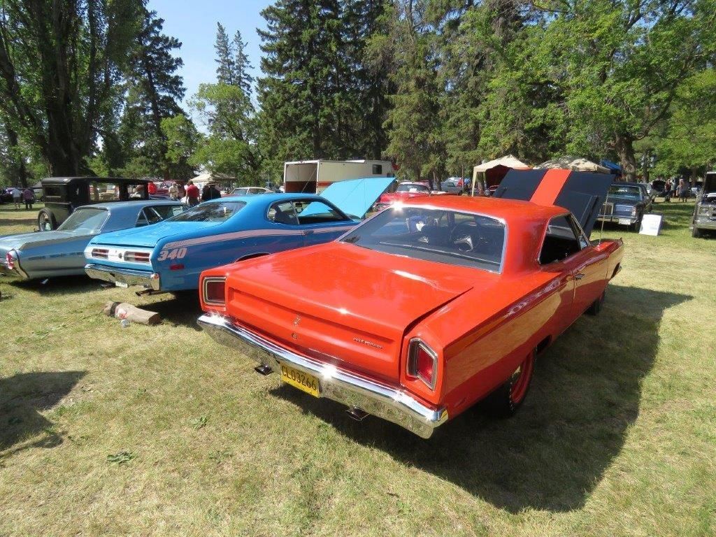 A red car is parked next to a blue car at a car show