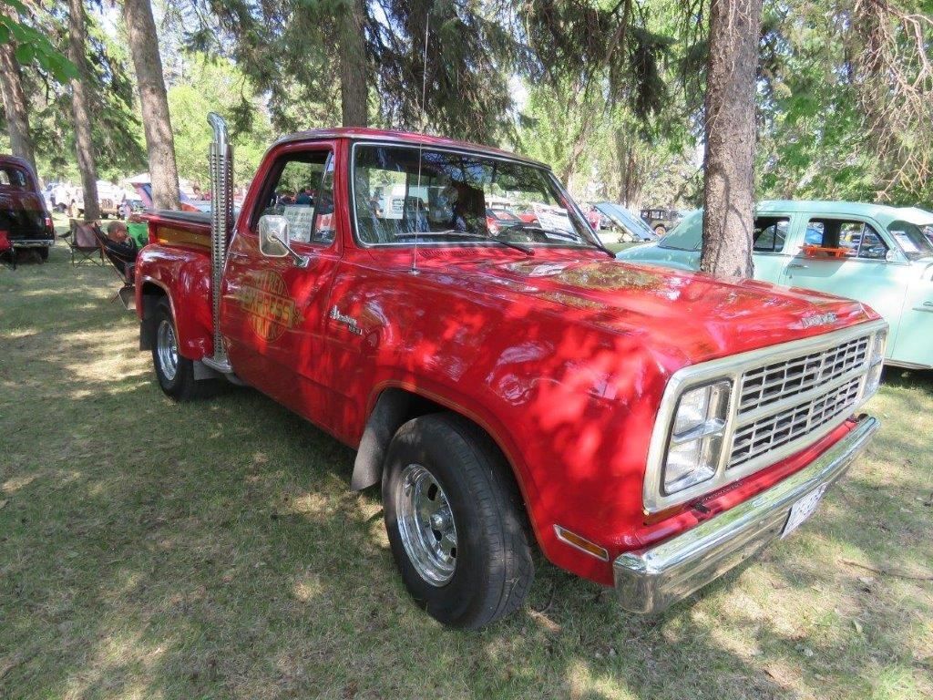 A red truck is parked in the grass at a car show.