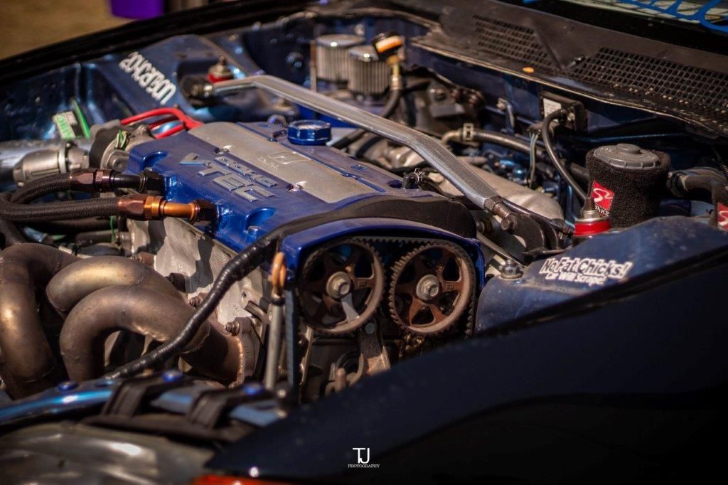 A close up of the engine of a car with the hood open.