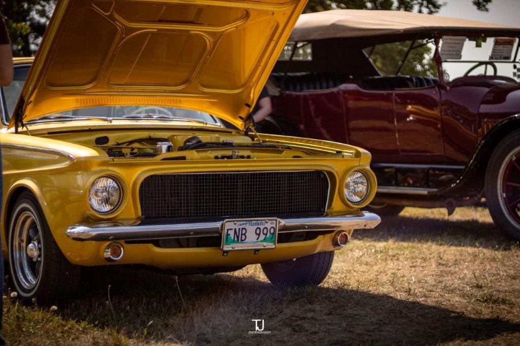 A yellow car with the hood up is parked next to a red car.