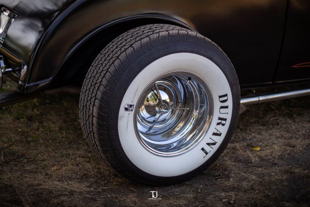 A close up of a tire on a black car with white tires.