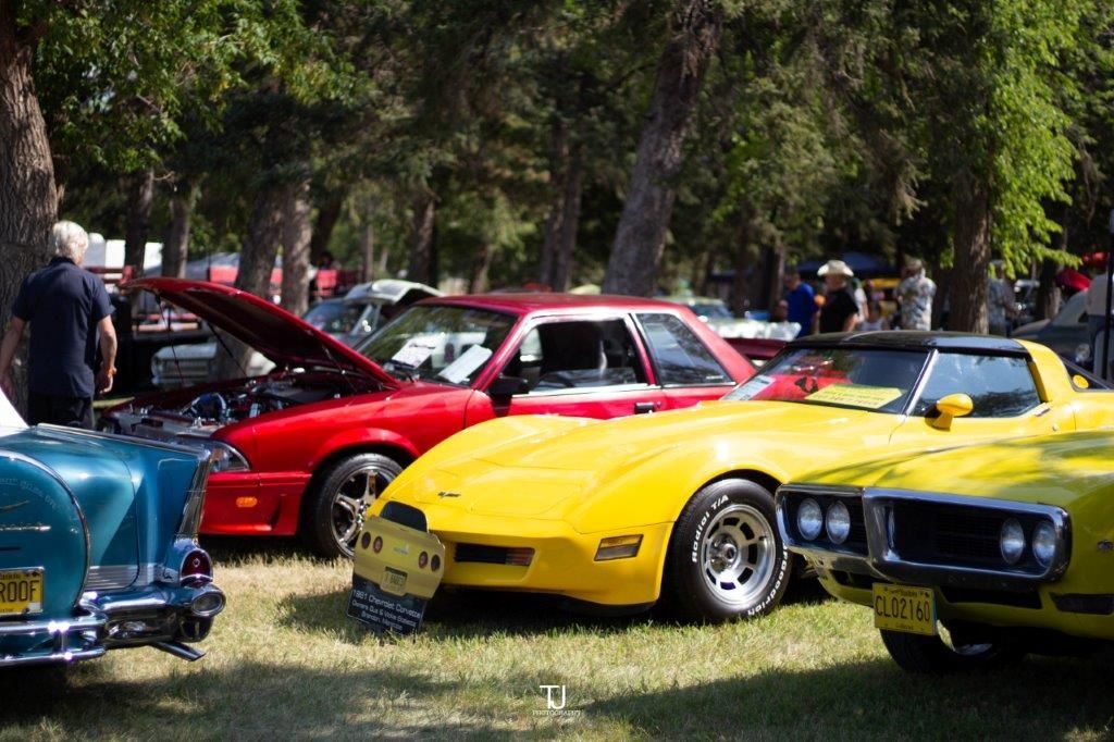 A yellow car is parked next to a red car at a car show.