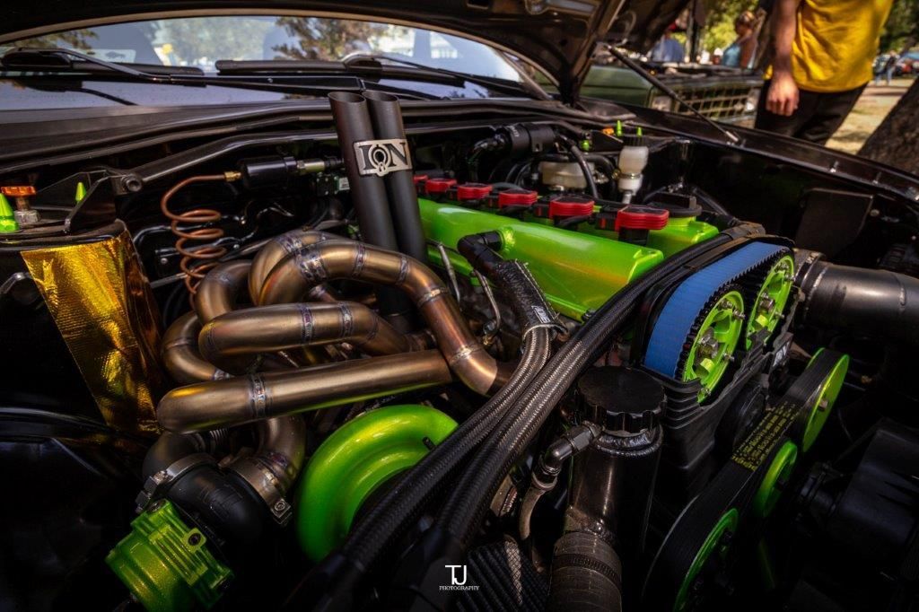 A close up of the engine of a car with the hood open.