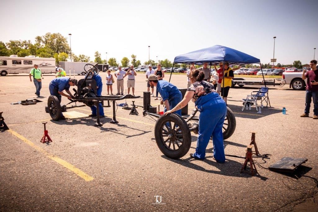 A group of people are working on a car in a parking lot