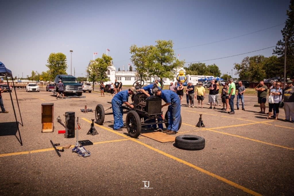 A group of people are working on a car in a parking lot.