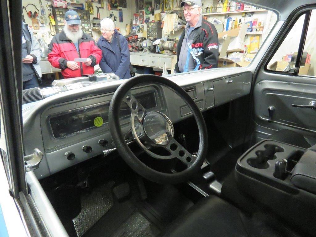 A group of men are looking at the interior of an old truck.