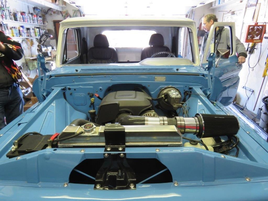 A blue car is being worked on in a garage