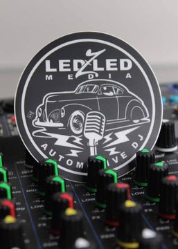 Black and white sticker with a classic car and microphone on a sound mixing board. LED Z Media Automotive DJ logo.