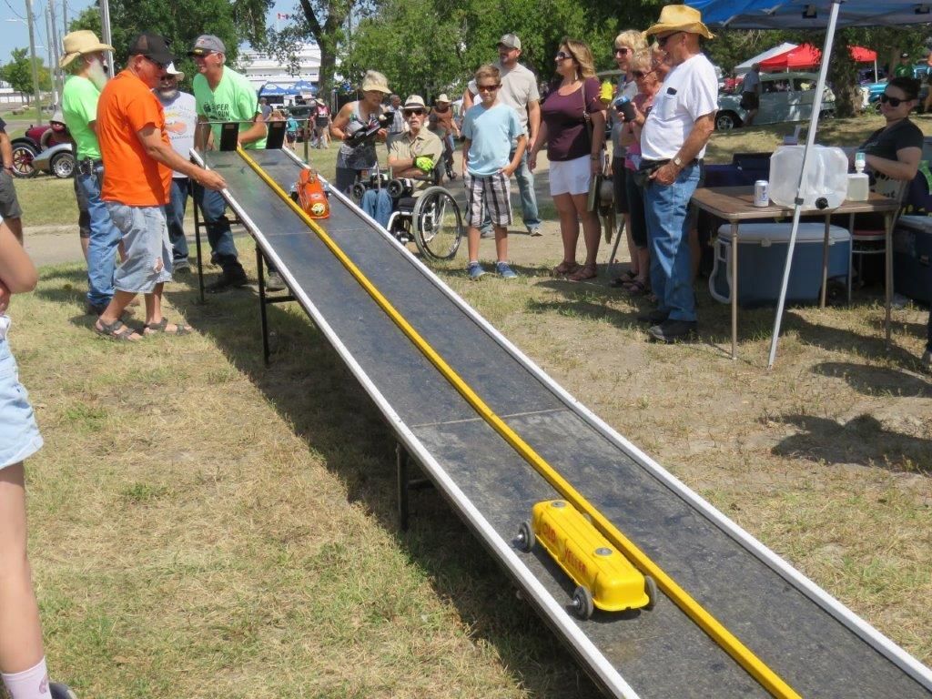 A group of people are watching a yellow toy train on a track