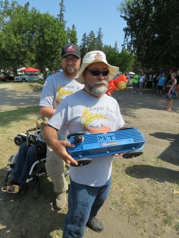 A man in a hat is carrying a blue skateboard