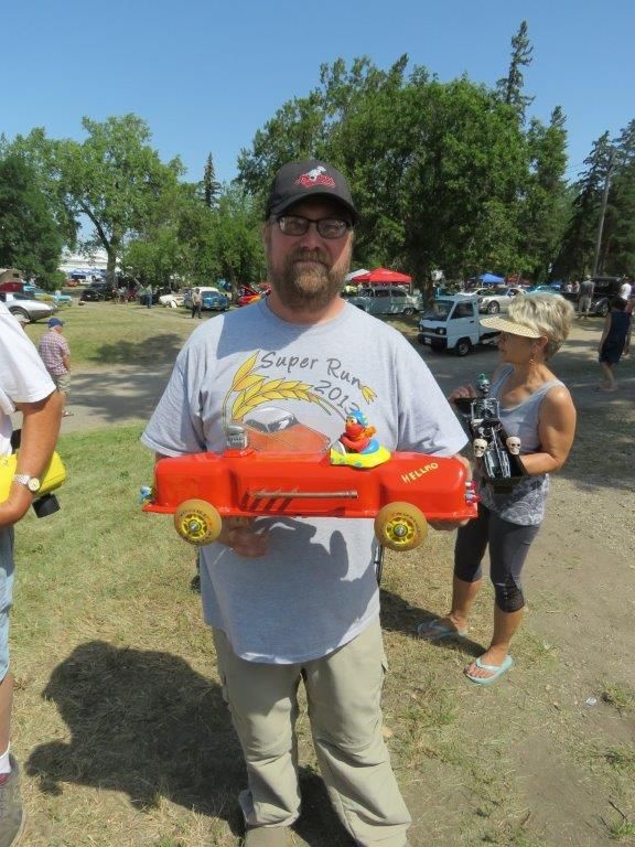 A man wearing a shirt that says super run 2013 is holding a toy truck