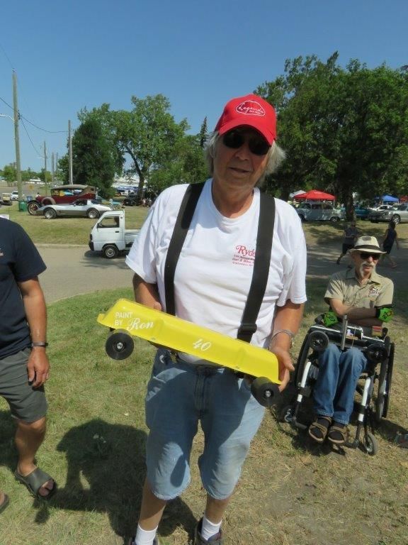 A man in a red hat is holding a yellow toy car
