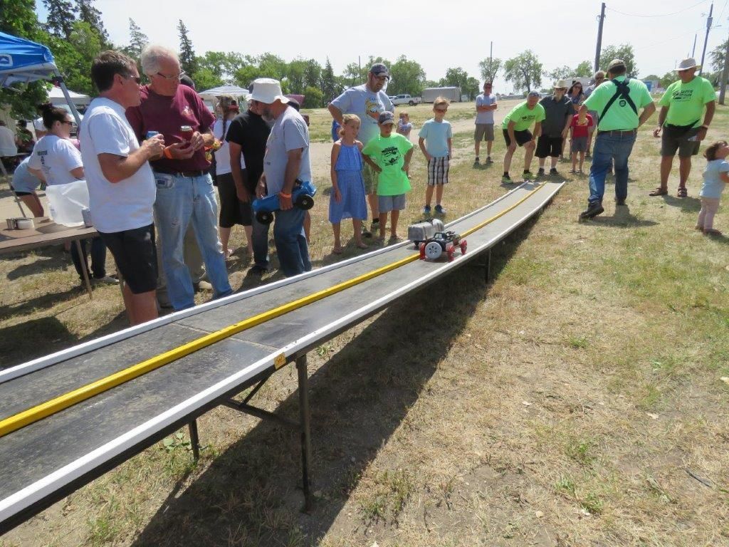 A group of people are watching a remote control car race on a track.