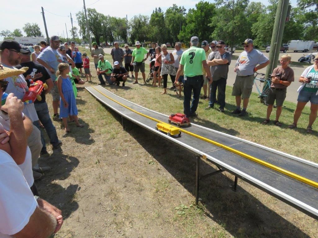 A group of people are watching a toy car race on a track.