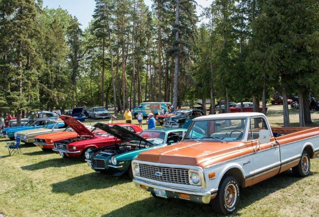 A row of old cars are parked in a grassy field.