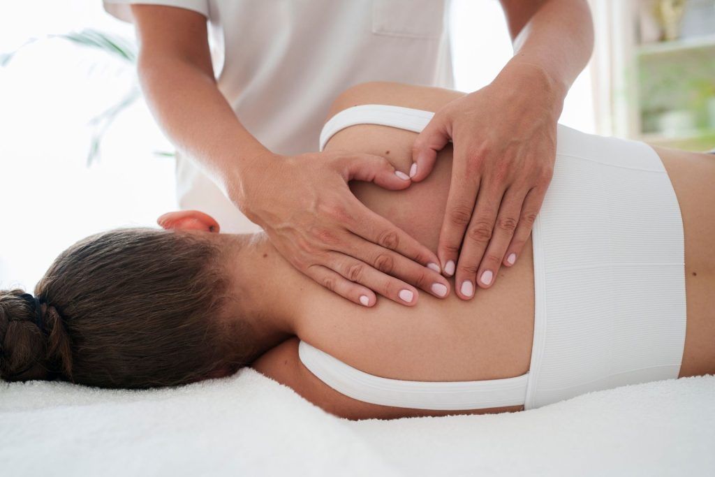 Massage therapist giving a shoulder massage, making a heart shape with hands.